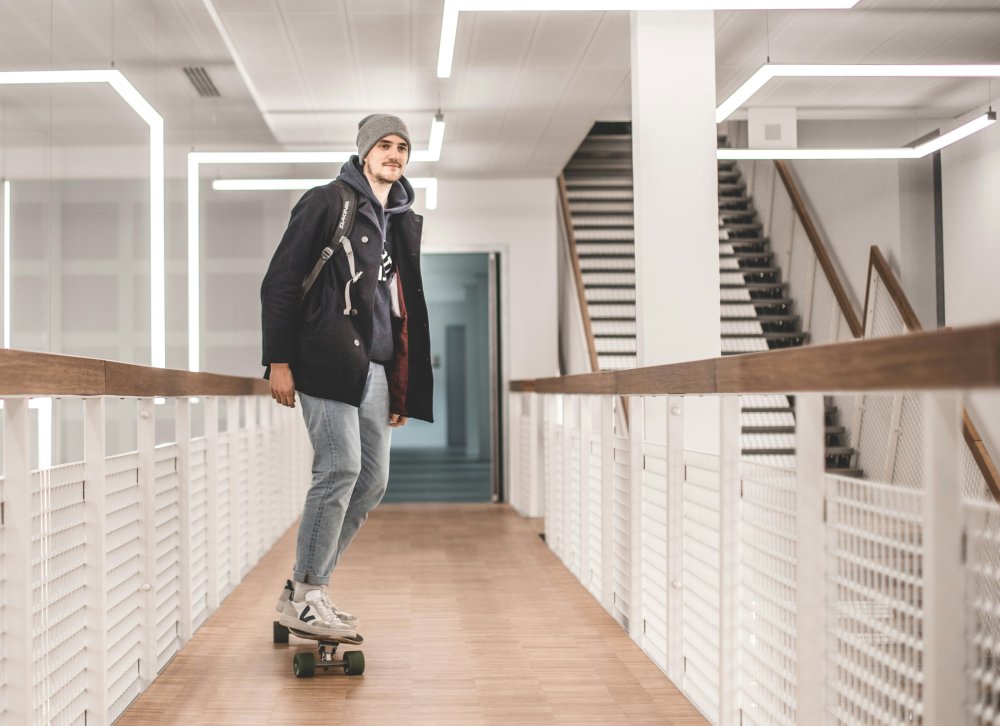 muž jedoucí na longboardu v chodbě